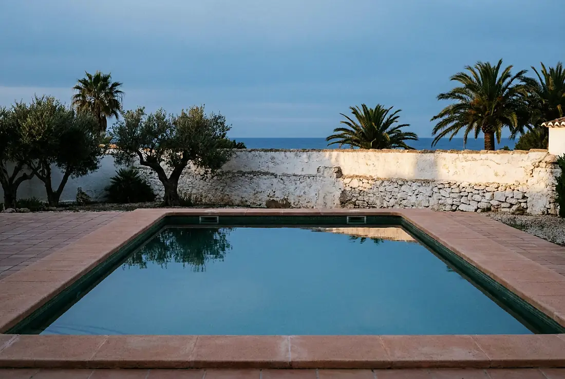 Piscine d'une villa espagnole éclairée en fin de journée, terrasse déserte